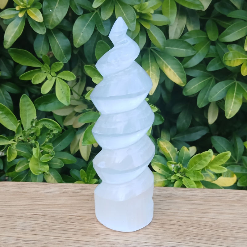 White spiral selenite carving on wooden surface